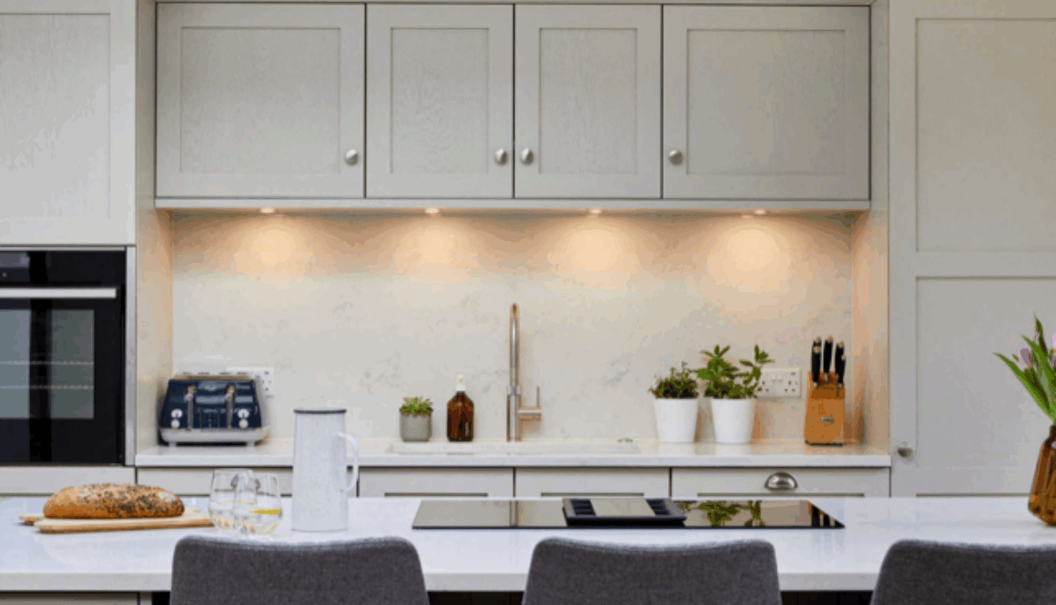 Modern kitchen with LED under cabinet puck lights illuminating white countertops and cabinets, showcasing a bright and energy efficient lighting upgrade